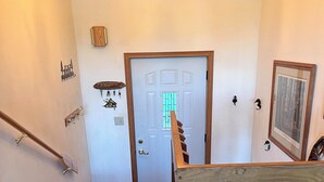 A wooden staircase with a handrail, a chandelier, and a door with a window.