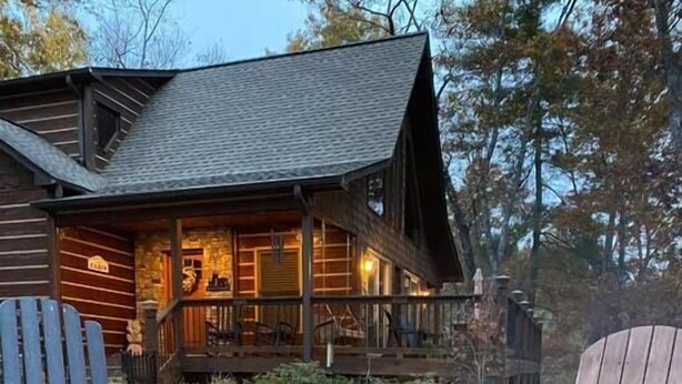 Eine rustikale Holzhütte mit einem Steinkamin und zwei Adirondack-Stühlen.