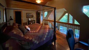 Ein Schlafzimmer mit Himmelbett, Schreibtisch mit Stuhl und einem Balkon mit Blick ins Freie.