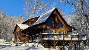 Eine Holzhütte mit einem Balkon, umgeben von schneebedeckten Bäumen.