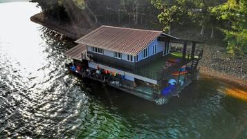 A riverside house with a dock, a covered deck, and a small boat.