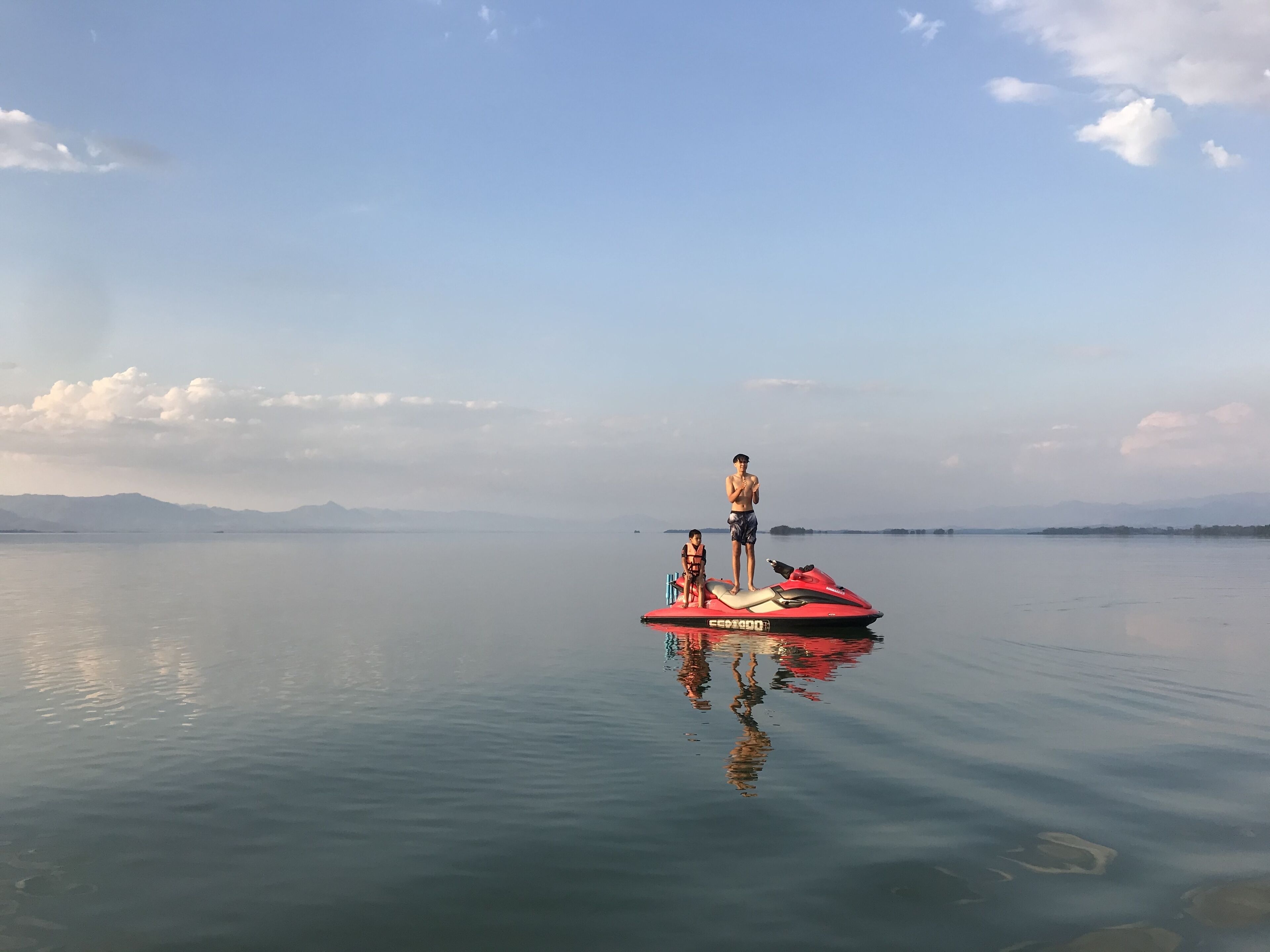 Um lago tranquilo com um jet ski vermelho ao centro.