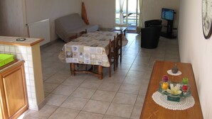 Eine kleine Küche mit Esstisch, Stühlen, einem kleinen Fernseher und einer Uhr an der Wand.
