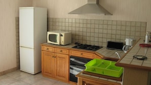 Eine kompakte Küche mit Kühlschrank, Mikrowelle, Herd und einem kleinen Spülbecken.