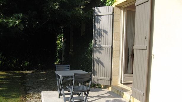 Eine Terrasse im Freien mit Tisch und Stühlen, einer Betonplattform und einer Holztür.