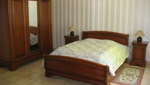 Ein Schlafzimmer mit einem hölzernen Bett, einem Kleiderschrank, zwei Nachttischen und einem Teppich.