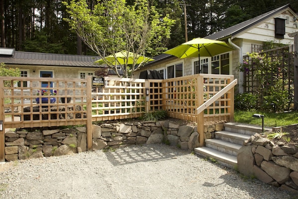 A guest parking area with a wooden fence, stone steps, and a green umbrella.