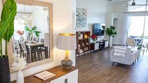 Una sala de estar moderna con una mesa de comedor de madera, un sofá, un televisor y una estantería.