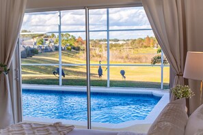 Una camera da letto con una grande finestra che si affaccia su una piscina e un campo da golf.