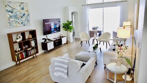 Una sala de estar moderna con un sofá, sillones, una mesa de centro, un televisor y una estantería.