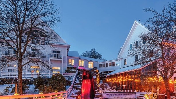 Un hotel con un paisaje nevado, una cascada y luces navideñas.