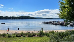 Vista de un lago con un muelle, barcos y gente en la orilla.