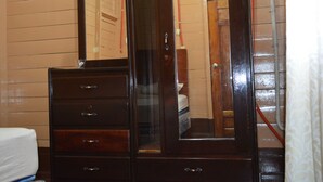 A wooden dresser with a mirror, drawers, and a small bedside table.