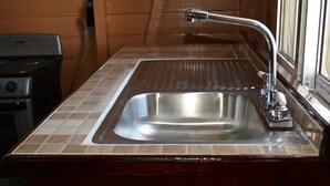 A kitchen with a stainless steel sink, a stove, and a window.