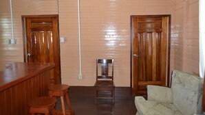 A room with wooden panel walls, a bar area with stools, a wooden chair, and a cushioned sofa.