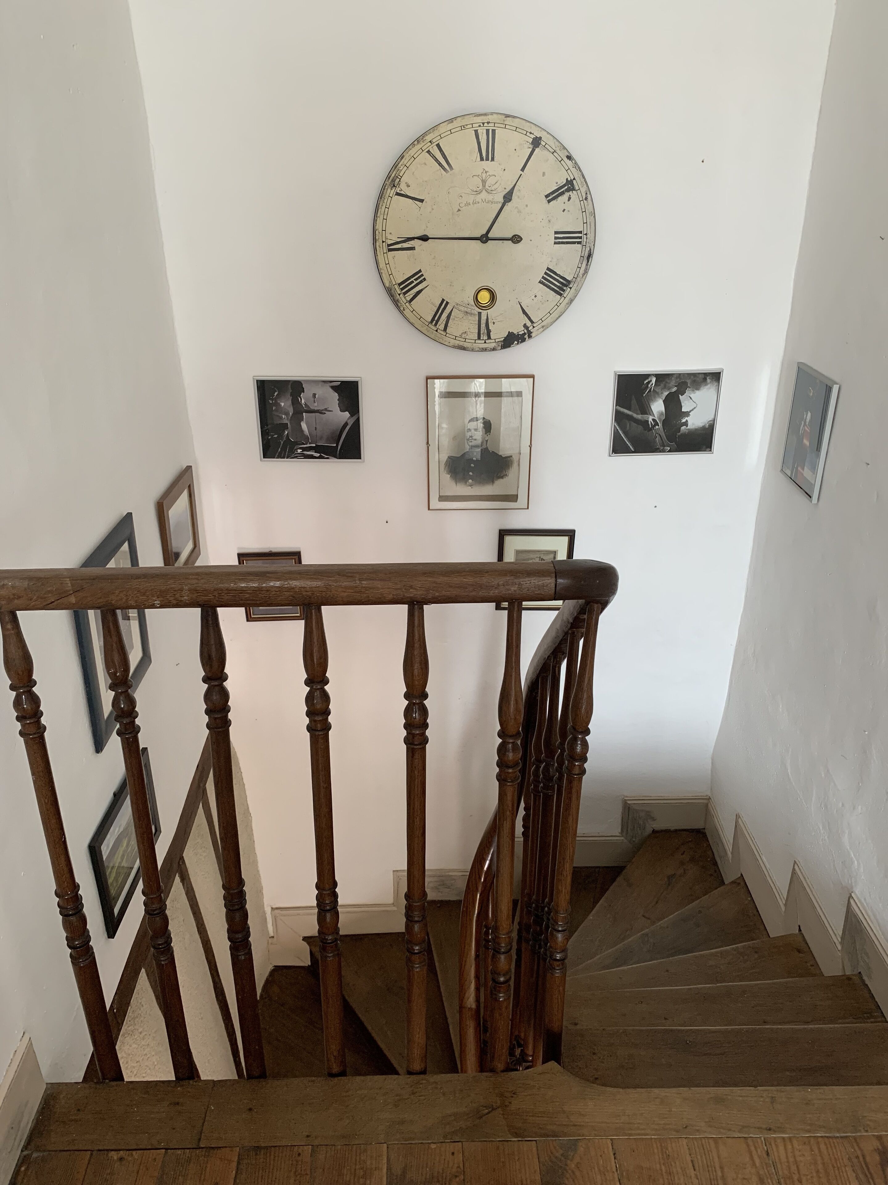 A wooden staircase with a clock on the wall above.