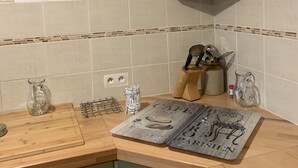 Eine Küche mit einem 'Bistro'-Schild, einer Holzarbeitsplatte, einer Karaffe, einem Messerblock und einem Schrank mit Spiegel.