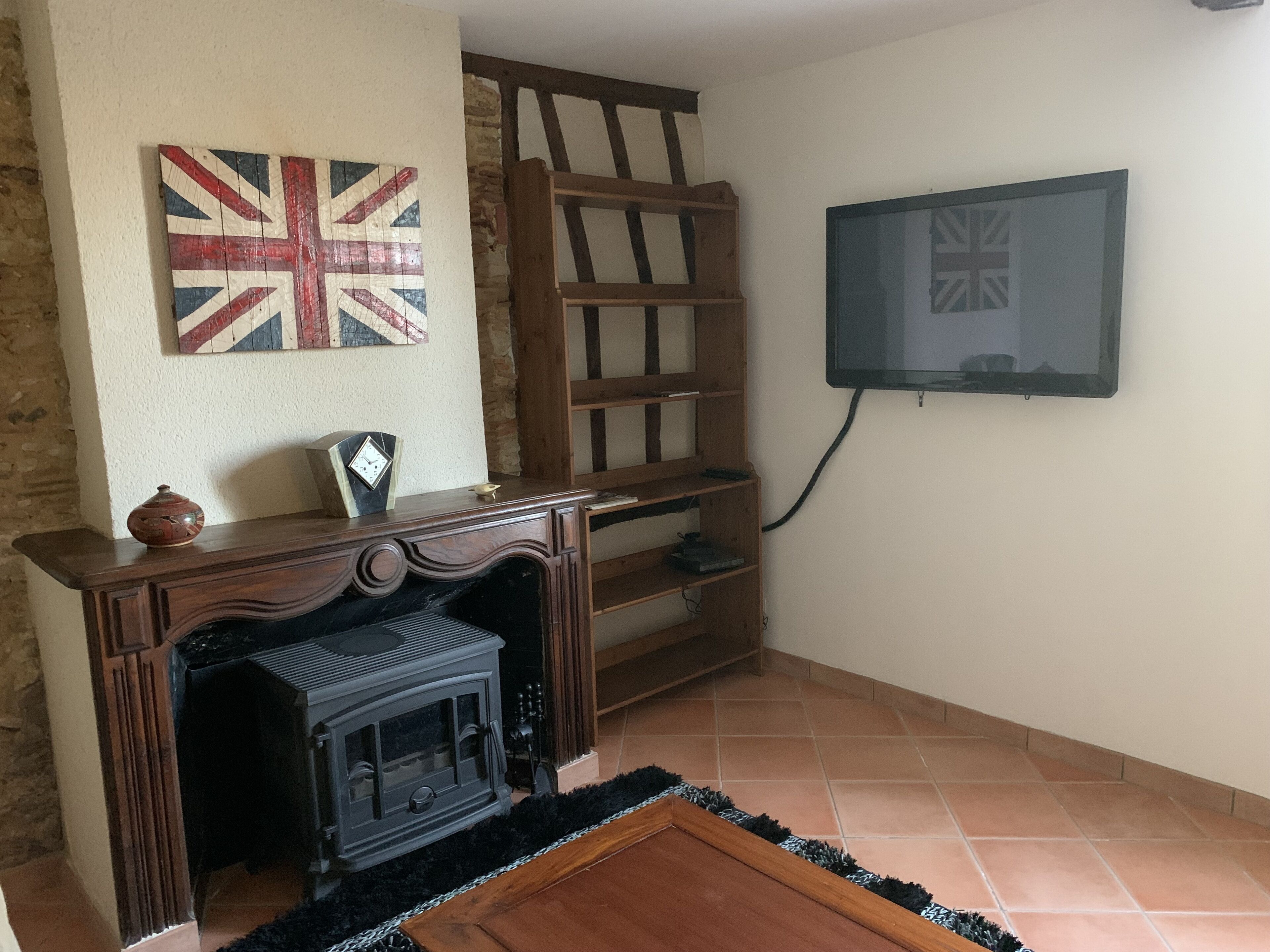 Una sala de estar con chimenea, estanterías de madera, televisor montado en la pared y una bandera Union Jack.