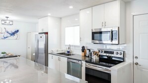 Una cocina moderna con electrodomésticos de acero inoxidable, armarios blancos y una isla grande.