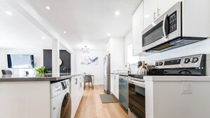 Una cocina moderna con lavadora, microondas, horno y comedor con mesa y sillas.