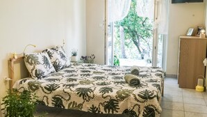 Ett sovrum med en säng, ett sängbord, en lampa, en tv och utsikt över grönområden utanför.