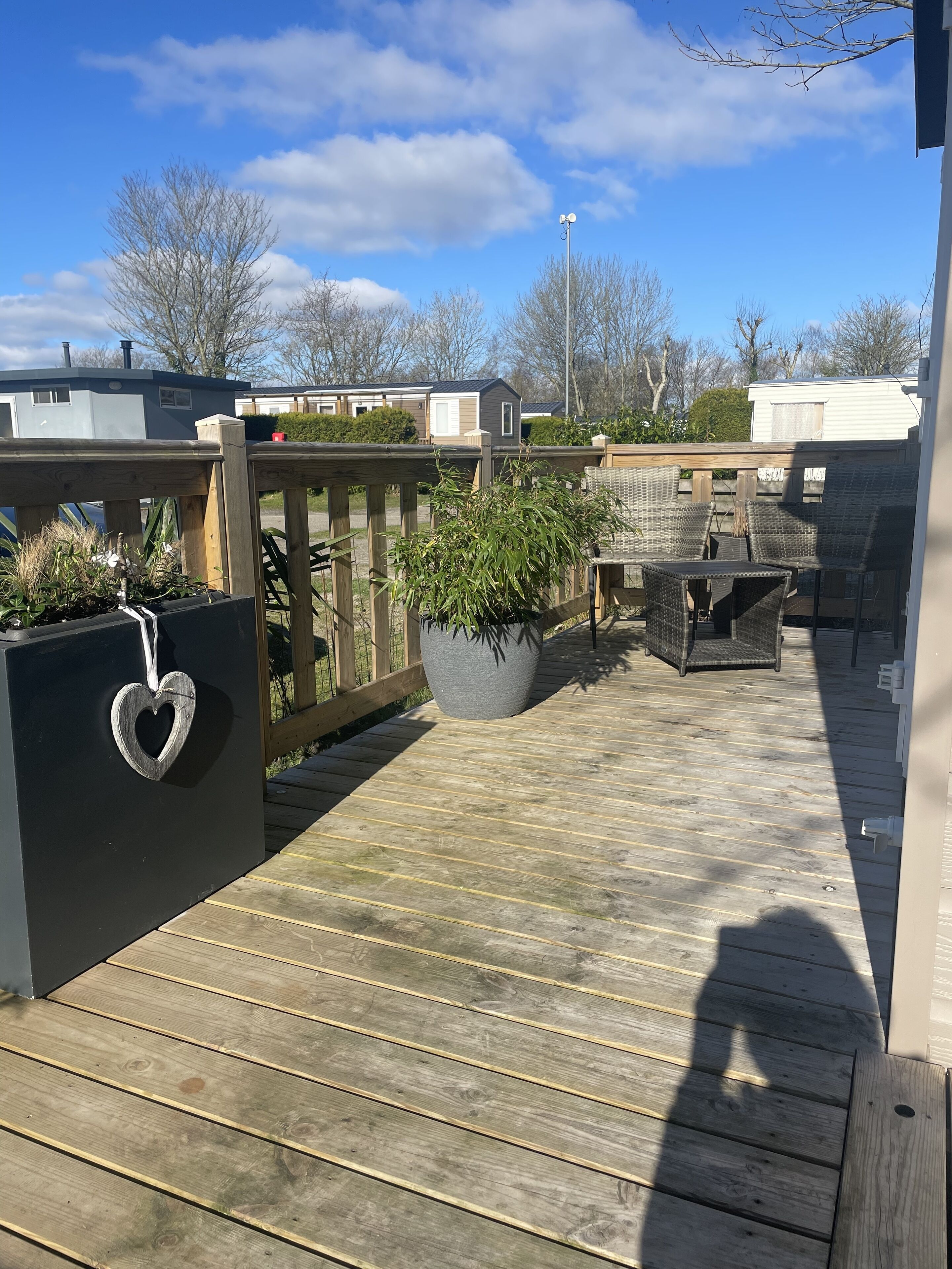 A wooden deck with a heart-shaped planter and wicker furniture.
