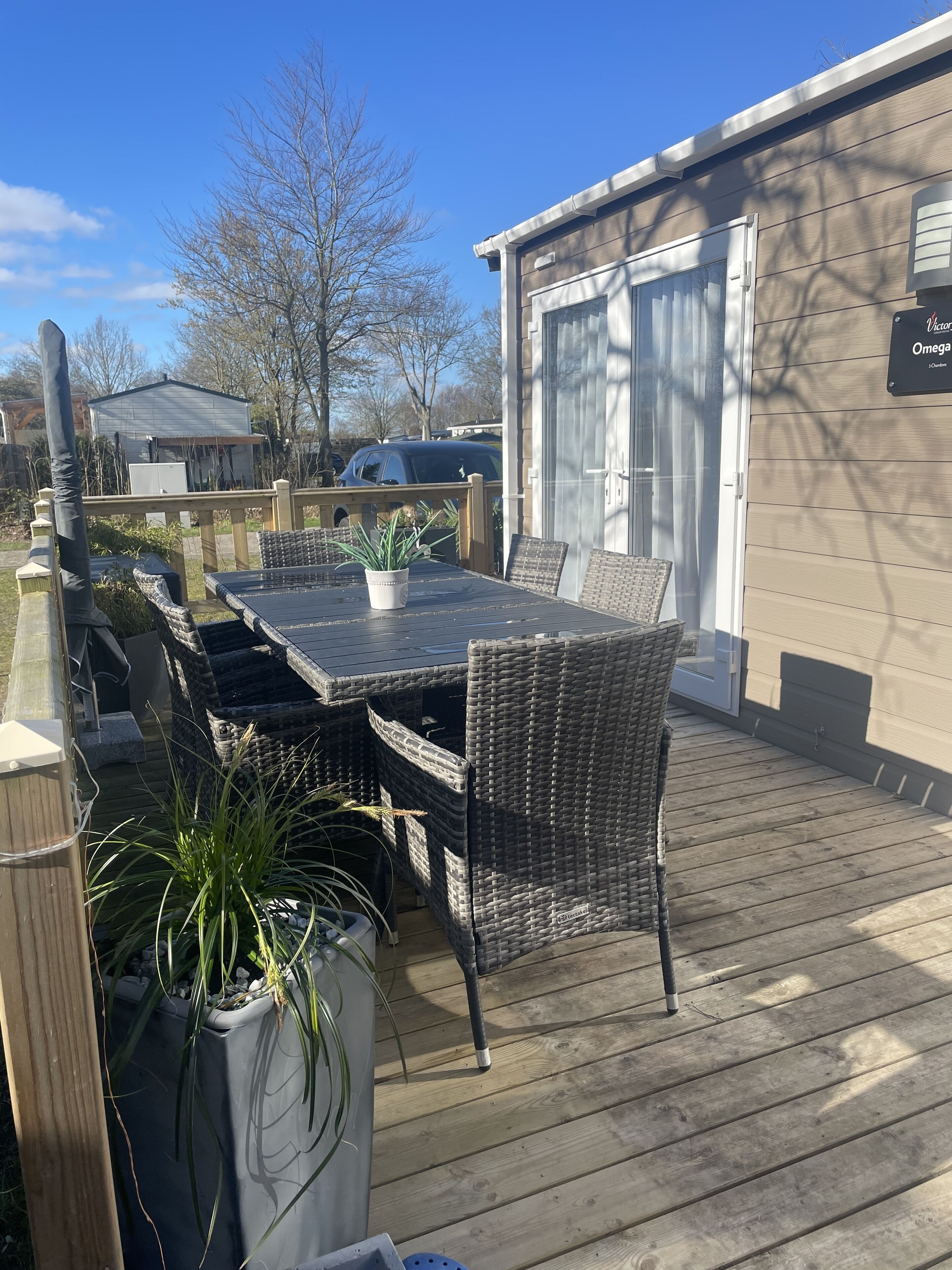 Eine Terrasse mit Tisch, Stühlen, einem Blumentopf und einem Gebäude mit einem Schild.