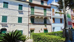 Un immeuble à plusieurs étages, avec des murs en pierre, des volets verts et des balcons.