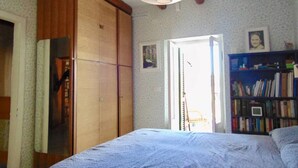 Une chambre à coucher comprenant un lit, une armoire en bois, une bibliothèque et une porte donnant sur l’extérieur.