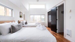 A modern hotel room with two beds, a skylight, a dark door, and a view of the outdoors. - Modern Central District Townhouse — 1 Block from Judkins Park Light Rail, Patio (Seattle)