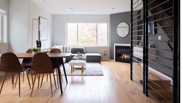 A modern living room with a fireplace, a dining area with a table and chairs, and a large window with a view of trees. - Modern Central District Townhouse — 1 Block from Judkins Park Light Rail, Patio (Seattle)