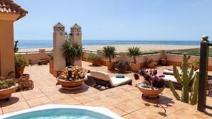 A rooftop terrace with a pool, lounge chairs, and potted plants overlooking a beach. - Stunning apartment in Ayamonte with swimming pool (Ayamonte)