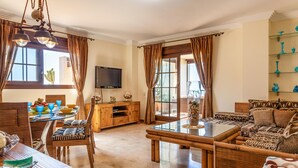 A spacious living room with a dining area, a television, and a glass coffee table. - Stunning apartment in Ayamonte with swimming pool (Ayamonte)