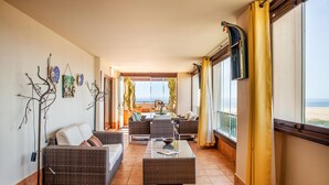 A sunlit corridor with wicker furniture, a view of the sea, and a balcony with yellow curtains. - Stunning apartment in Ayamonte with swimming pool (Ayamonte)
