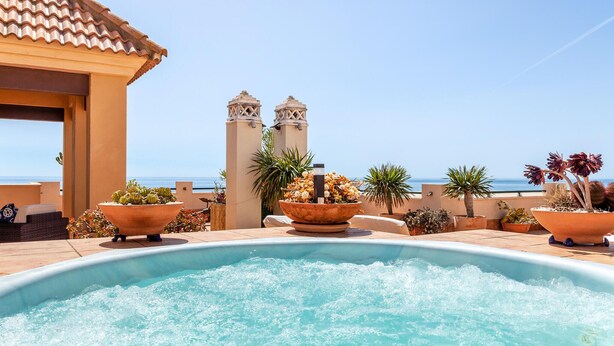 A rooftop pool area with a clear view of the sea, surrounded by potted plants and a building with a tiled roof. - Stunning apartment in Ayamonte with swimming pool (Ayamonte)