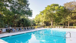 Une piscine équipée de chaises longues et d’un panneau indiquant une zone peu profonde où il est interdit de plonger.