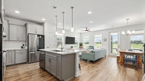 Una cocina moderna con una isla grande, electrodomésticos de acero inoxidable e iluminación colgante.