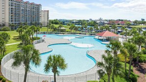 Un hotel con una amplia piscina rodeada de palmeras y vistas a un paisaje urbano al fondo.