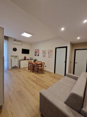 Un appartement moderne comprenant un coin repas, une kitchenette et un salon avec un canapé.