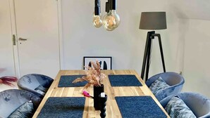 A conference room with a wooden table, black mats, leather chairs, a black lamp, and hanging light bulbs.