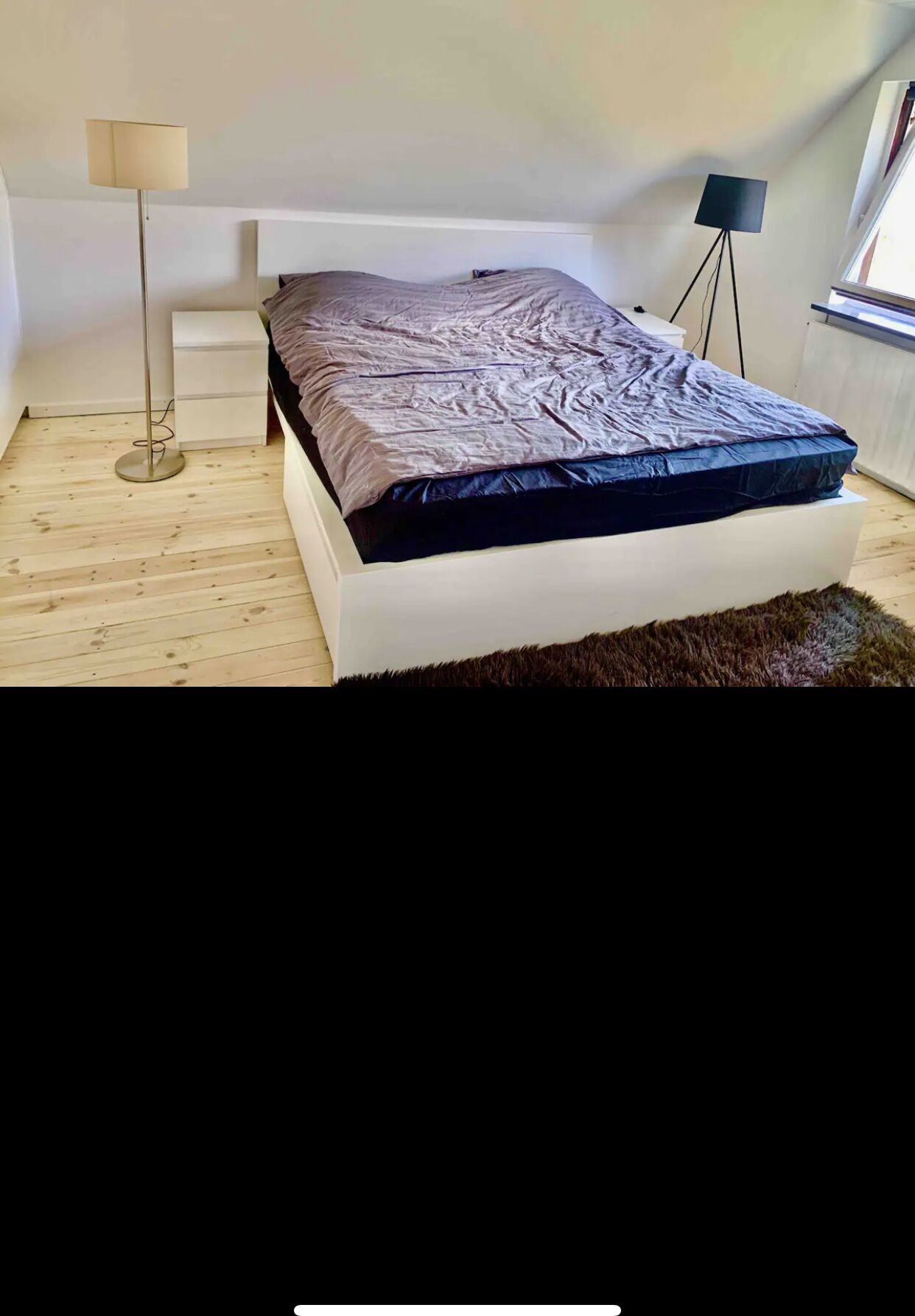 A bedroom with a bed, a standing lamp, and a floor lamp.