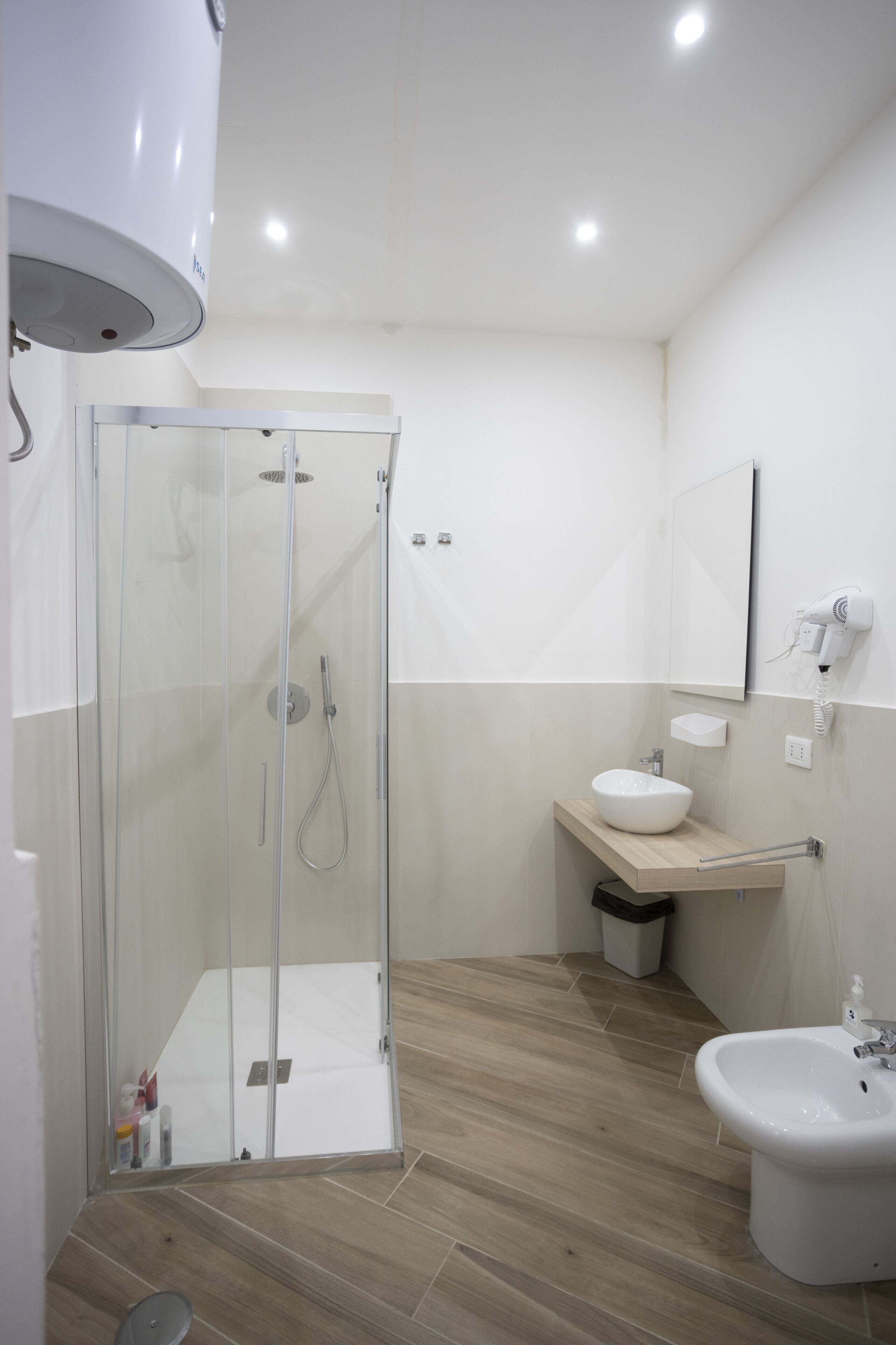 A modern bathroom with a glass-enclosed shower, a sink, and a bidet.