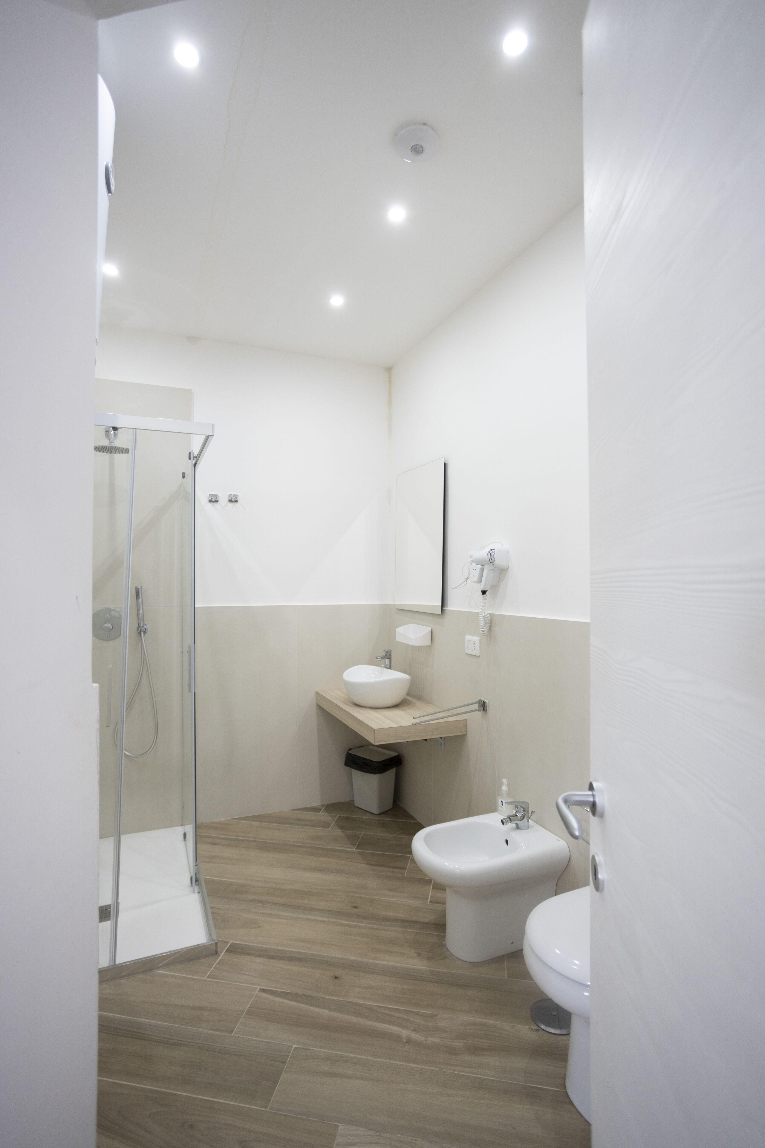 Un bany modern amb una cabina de dutxa de vidre, un lavabo, un vàter i un lavamaniges.
