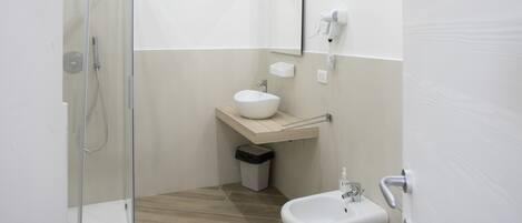 Un bany modern amb una cabina de dutxa de vidre, un lavabo, un vàter i un lavamaniges.