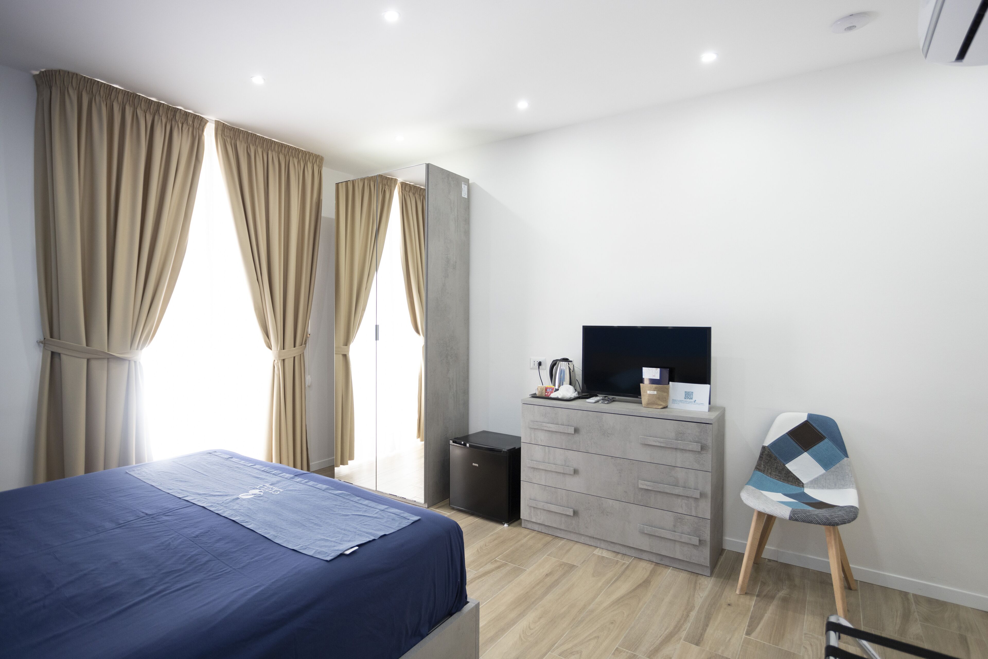 Un dormitorio con cama, cómoda, televisor y silla.