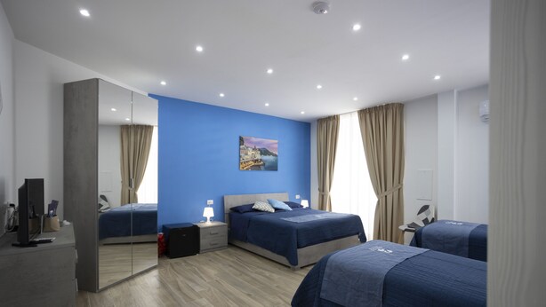 A modern hotel room with two beds, a large mirror, a flat-screen TV, and a painting on the wall. - GIULY SUITES & ROOMS (Naples)