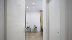 A narrow hallway with a mirrored wall, a wooden floor, and two chairs. - GIULY SUITES & ROOMS (Naples)