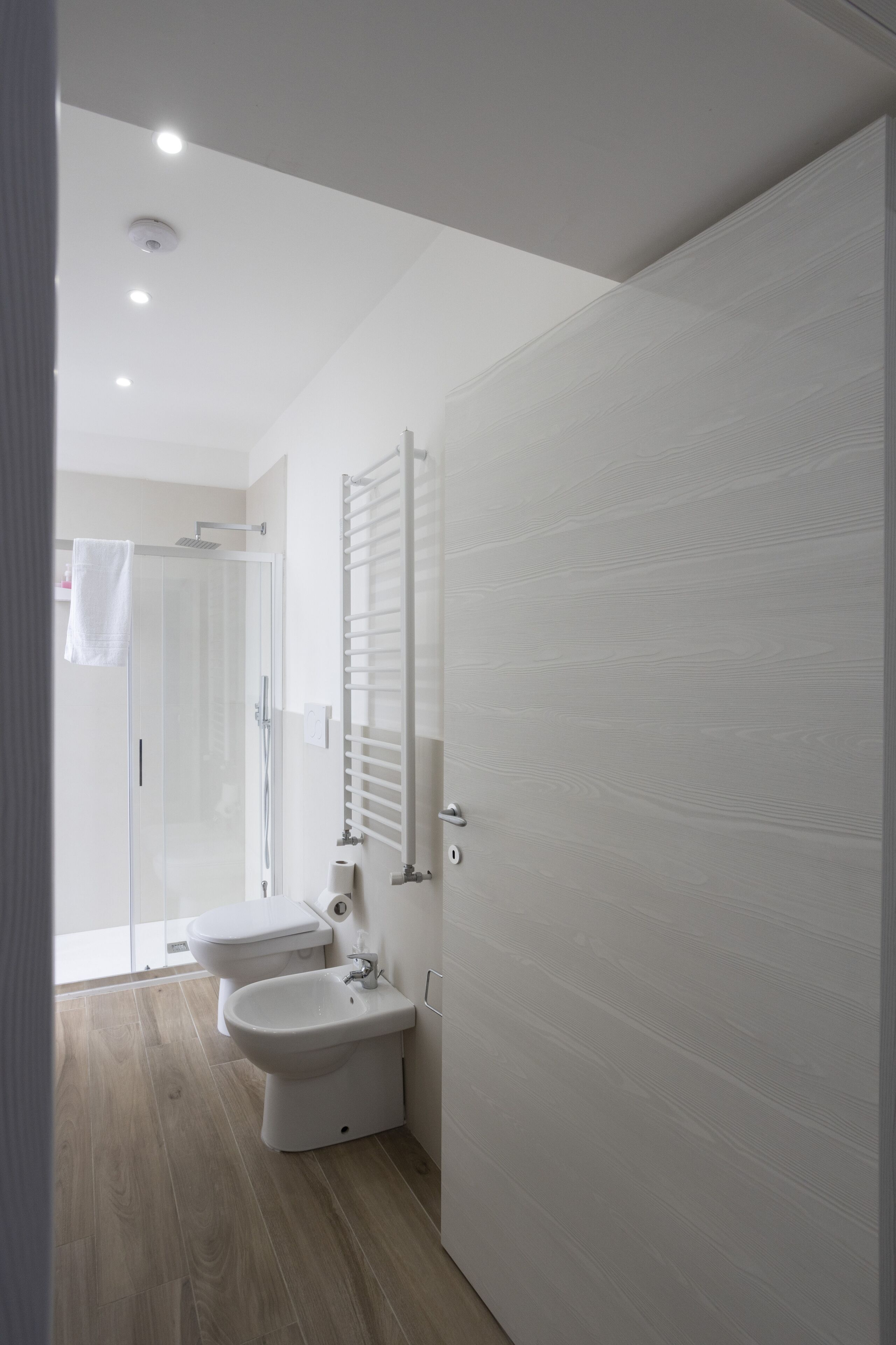 A modern bathroom with a glass shower enclosure, a toilet, and a bidet.