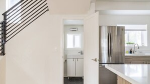 A modern kitchen with stainless steel appliances, a white countertop, and a wooden floor. - Central District 5BR — Walk to Capitol Hill, Cal Anderson Park & Broadway (Seattle)