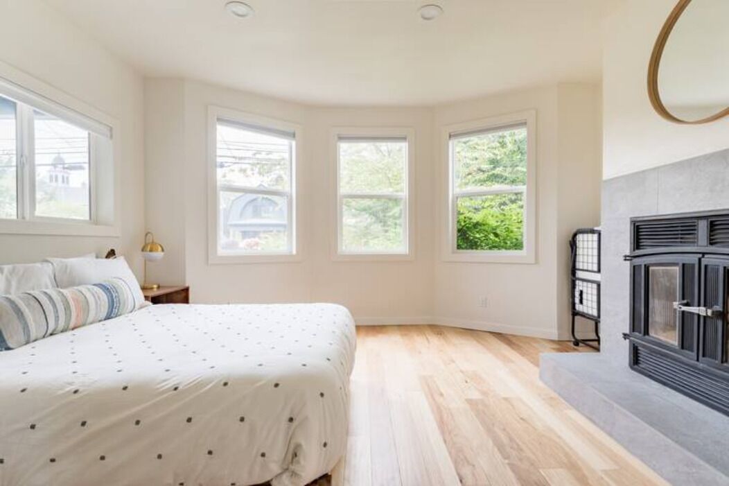 Une chambre à coucher avec un lit, une table de chevet, une cheminée et de grandes fenêtres.